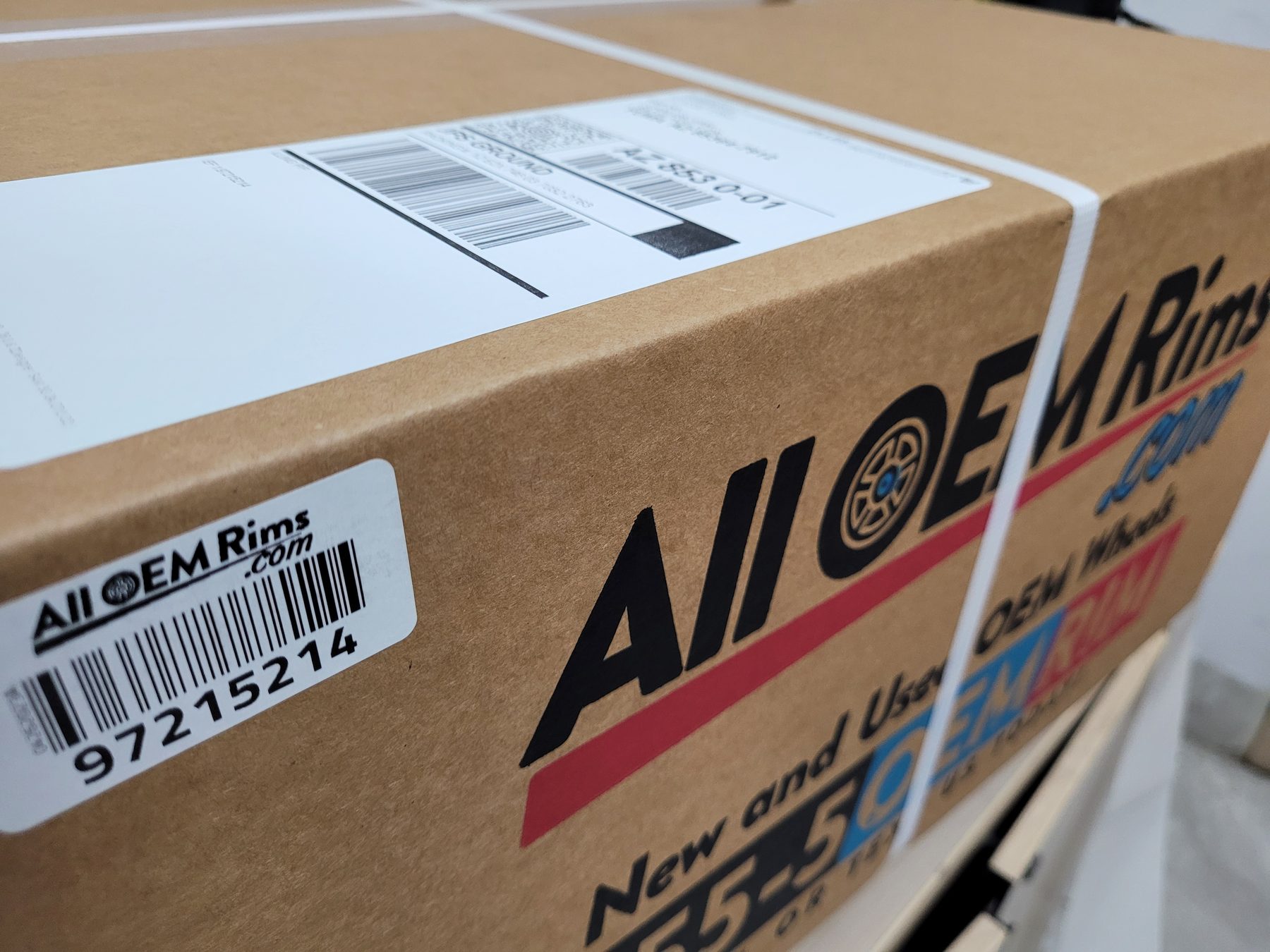 A finished AllOEMRims.com box, strapped and barcoded with its shipping label